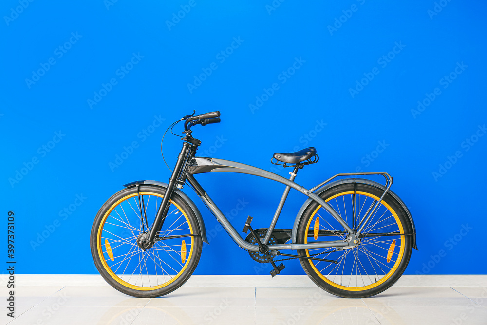 Fototapeta premium Modern bicycle against color wall