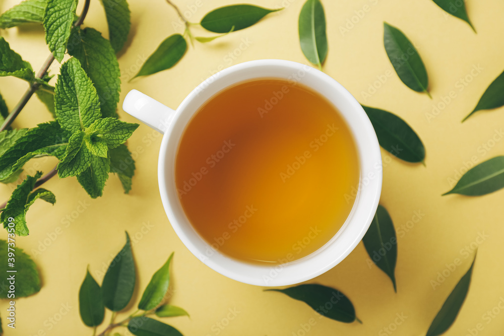 Cup of tea, mint and green tea leaves on color background Cup of tea, mint and green tea leaves on color background