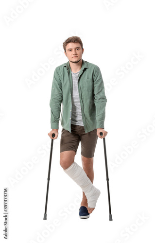 Young man with broken leg on white background © Pixel-Shot