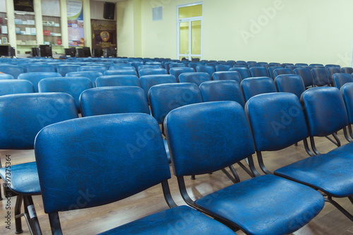 Empty big Assembly hall with lots of blue chairs without people
