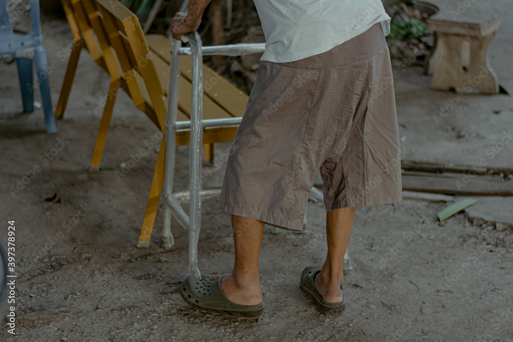 An exhausted old man walking with walker at home.
