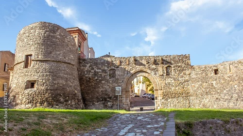 Time lapse of Melfi's castle, a medieval stone bricks castle with towers in south of Ttaly during a sunny cloudy day. There is a stone bridge and tower and countryside around it