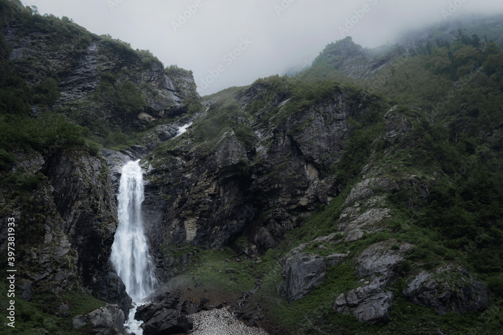 Moody Waterfall in the green mountains covered in mist
