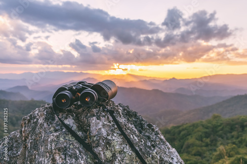 binoculars on top of rock mountain at sunset photo