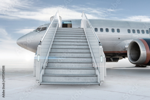 Passenger airplane with a boarding stairs on the airport apron isolated on bright background with sky photo