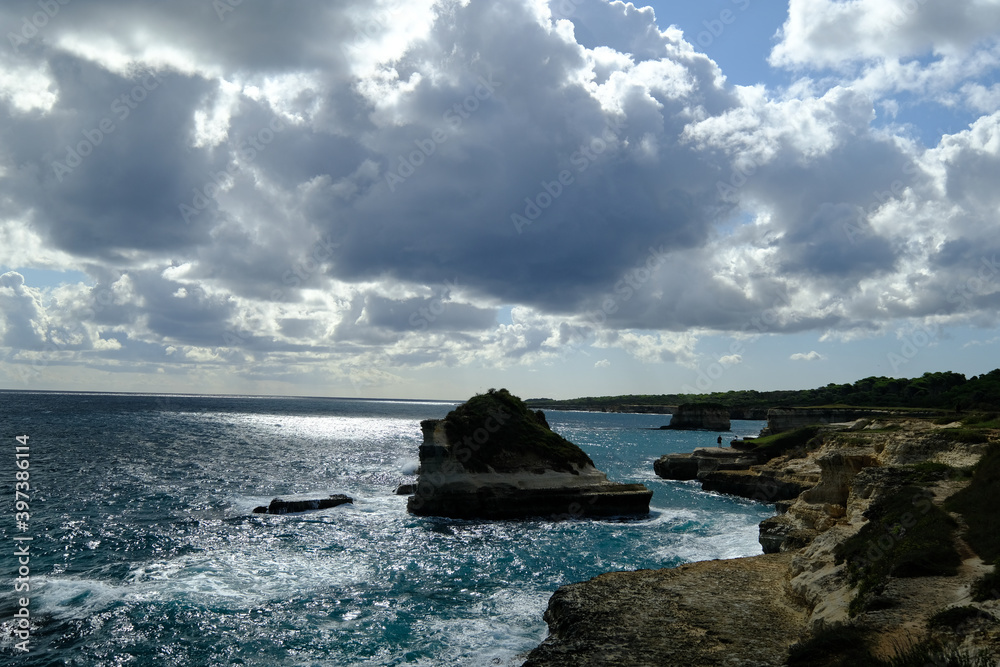 a rocky outcropping in the ocean with a cloudy sky