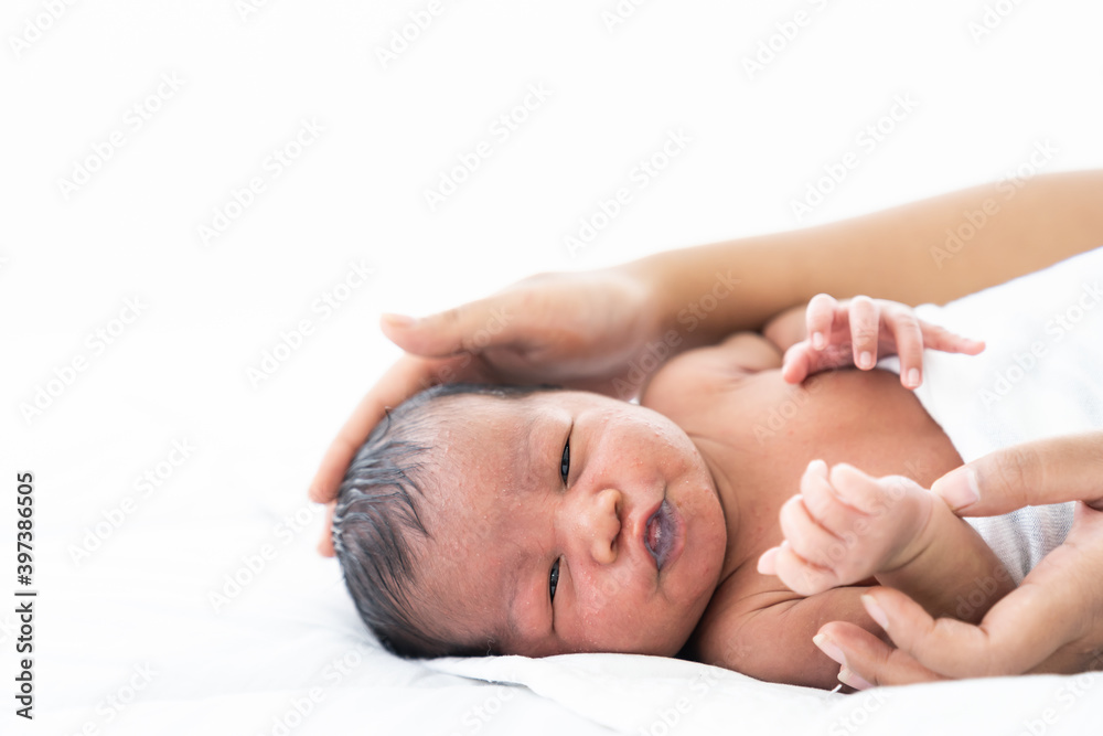 African American newborn baby or infant lying on white bed while mother’s hands takes care and comforting. Family, love and new life concept African American newborn baby or infant lying on white bed while mother’s hands takes care and comforting. Family, love and new life concept