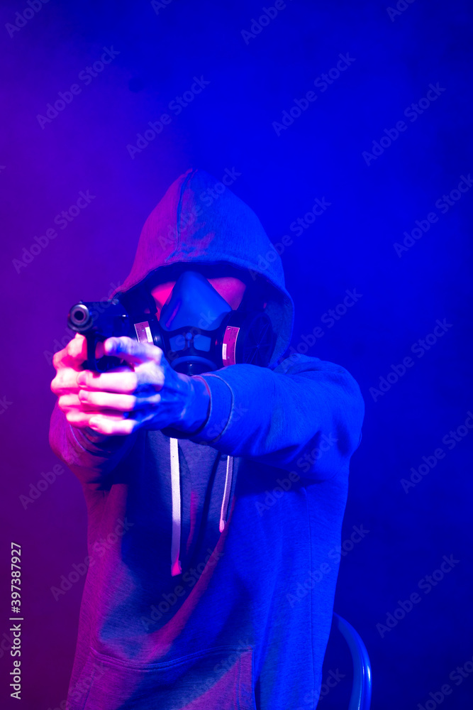 Selective focus of bi-racial cyberpunk player in mask holding guns near neon lighting surrounded by smoke. Soft focus effect.