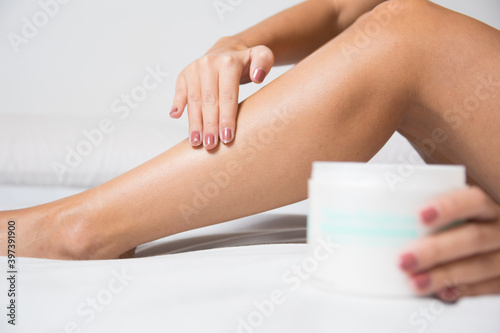 woman putting hand cream on her legs to keep them hydrated and healthy. Wellness, health and lifestyle concept