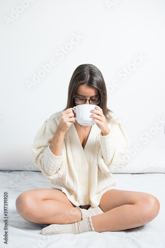 woman with glasses comfortable at home drinking a cup of coffee or tea with warm woolen clothes. Concept being at home