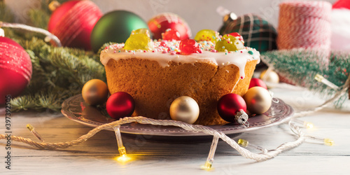 Sweet christmas cake with xmas holiday decor and lights. Traditional italian sweet casatiello bread with frosting and candied fruit photo