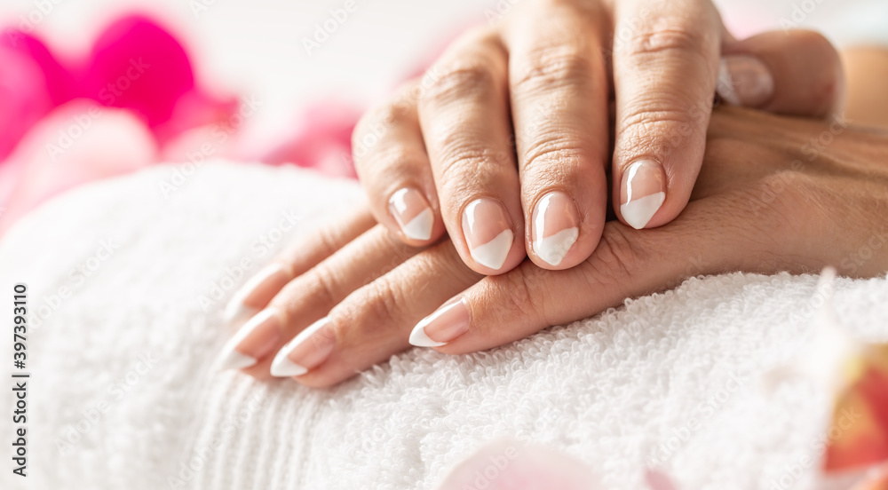 Nice uncolored nails of crossed hands on a white towel in a nail salon
