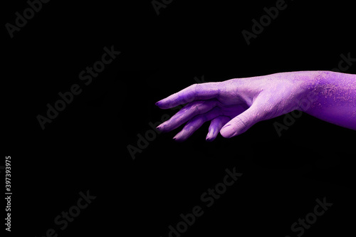 A beautiful purple female hand with dry skin stretches your product on a black isolated background, concept art