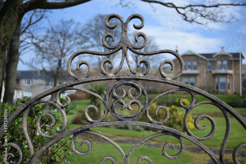 Close Up of Ornate Iron Work on Gated Entrance of Large Victorian House 