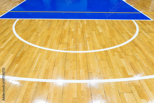 Top view of a part of an empty basketball court. the floor of the sports space is made of wood and painted blue
