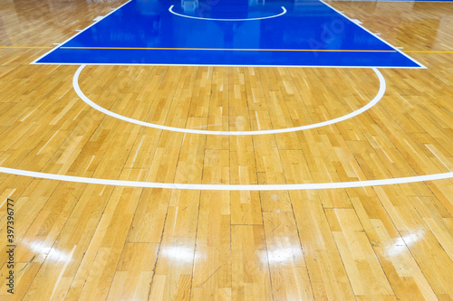 Top view of a part of an empty basketball court. the floor of the sports space is made of wood and painted blue