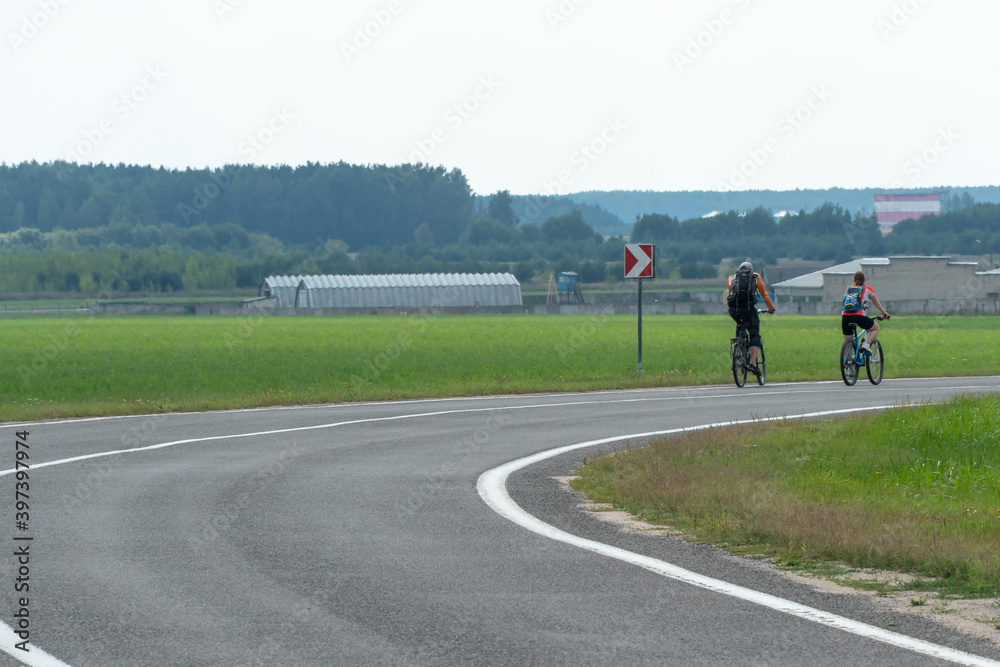 Empty asphalt road through woods and fields. New fresh asphalt pavement away from the city. Development of rural infrastructure. Road marking lines close up. cycle tourism Empty asphalt road through woods and fields. New fresh asphalt pavement away from the city. Development of rural infrastructure. Road marking lines close up. cycle tourism