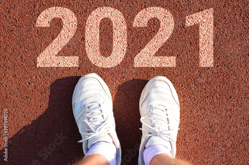 feet in sneakers on the treadmill and the inscription 2021. start of the new year, tasks, ideas, desires for the next year.