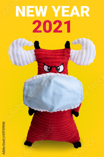 Red bull symbol of the new year 2021 in a medical mask. yellow background and inscription new year 2021