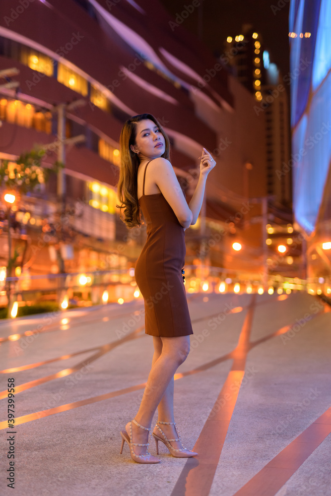 Full length shot of beautiful Asian woman outdoors in Bangkok, Thailand at night