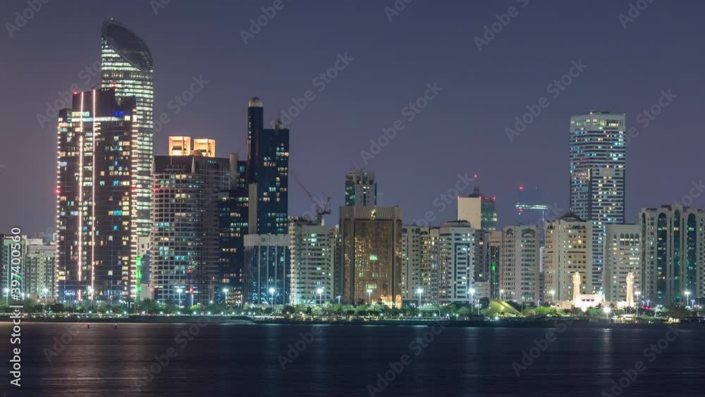 Panoramic view of Abu Dhabi Skyline and seafront at night timelapse, United Arab Emirates. View of Corniche with illuminated skyscrapers and mosque Panoramic view of Abu Dhabi Skyline and seafront at night timelapse, United Arab Emirates. View of Corniche with illuminated skyscrapers and mosque