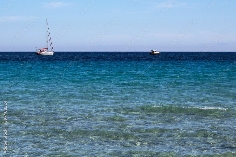 evocative image of the sea of many colors and boats in the background