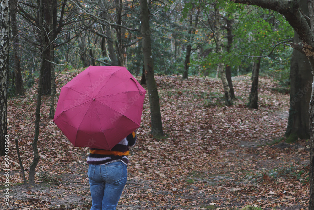 A woman with an umbrella in an autumn day in middle of the wood