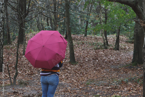 A woman with an umbrella in an autumn day in middle of the wood