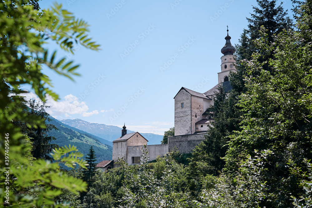 Beautiful summer landscape with ancient monastery in mountains. Benedictine Abbey of Monte Maria in the Venosta valley, South Tyrol, northern Italy, Europe.