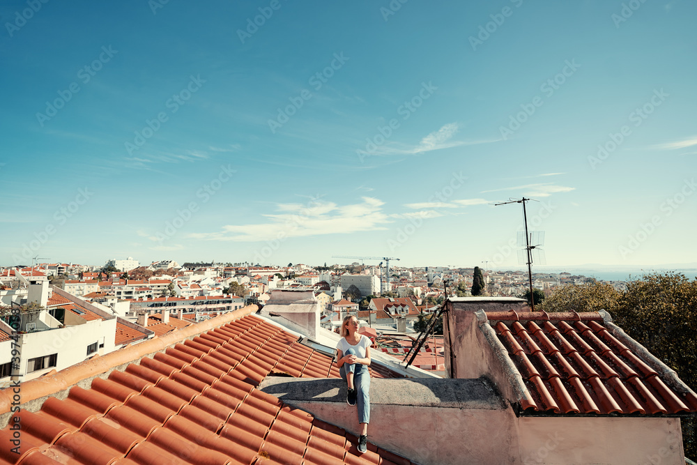 Traveling by Portugal. Young traveling woman enjoying old town Lisbon view on red tiled roof.
