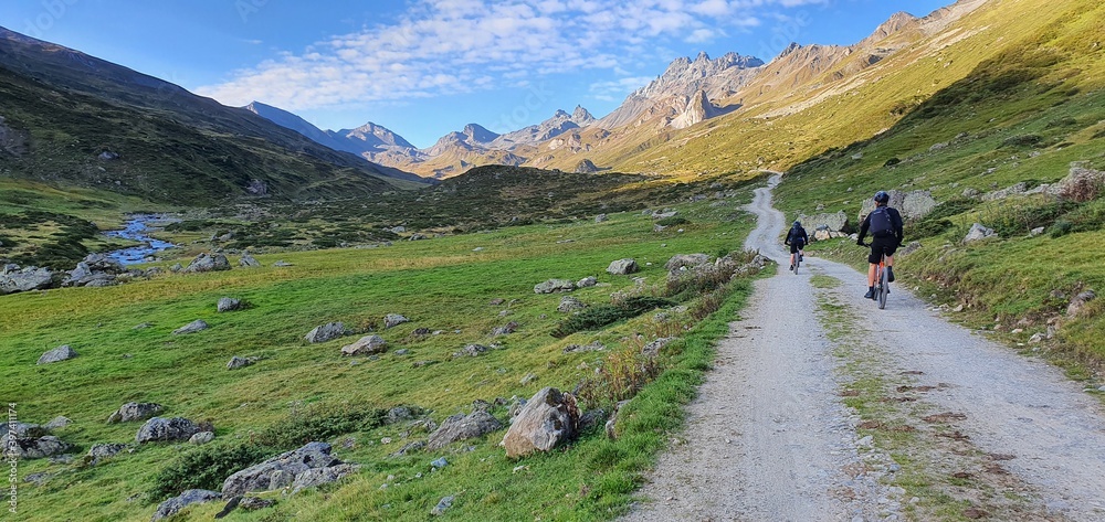 Group mountain cycling on a trekking path in austria alps in a green valley in summer 2020