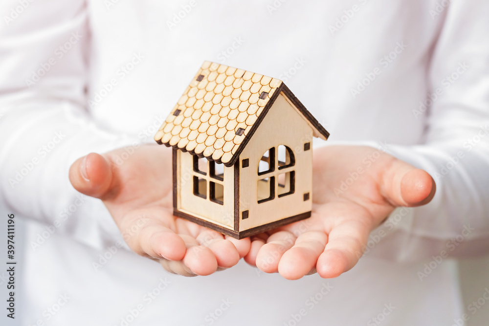 Children's hands hold a wooden house. Real estate concept, Social distancing new normal concept. Children's hands hold a wooden house. Real estate concept, Social distancing new normal concept.