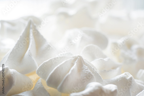 Blurred sweet crispy twisted meringue, zephyr, marshmallow made from egg whites, sugar and lemon on white food background. Selective focus, shallow depth of field.