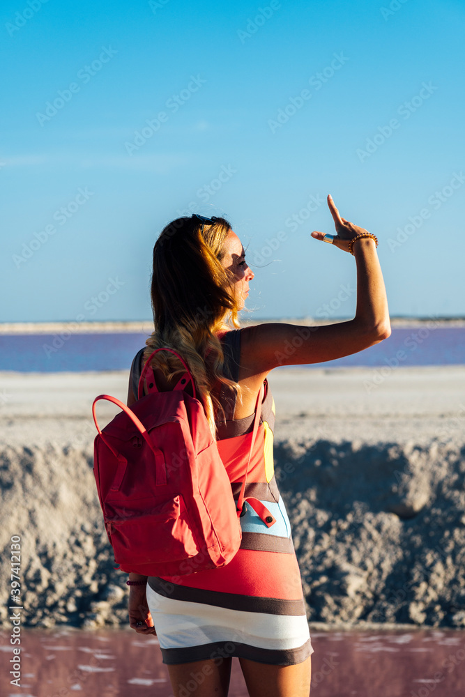 Back view of stylish middle aged tourist with backpack looking at distance while standing near pink lake and enjoying sunset in Las Coloradas, Mexico Back view of stylish middle aged tourist with backpack looking at distance while standing near pink lake and enjoying sunset in Las Coloradas, Mexico