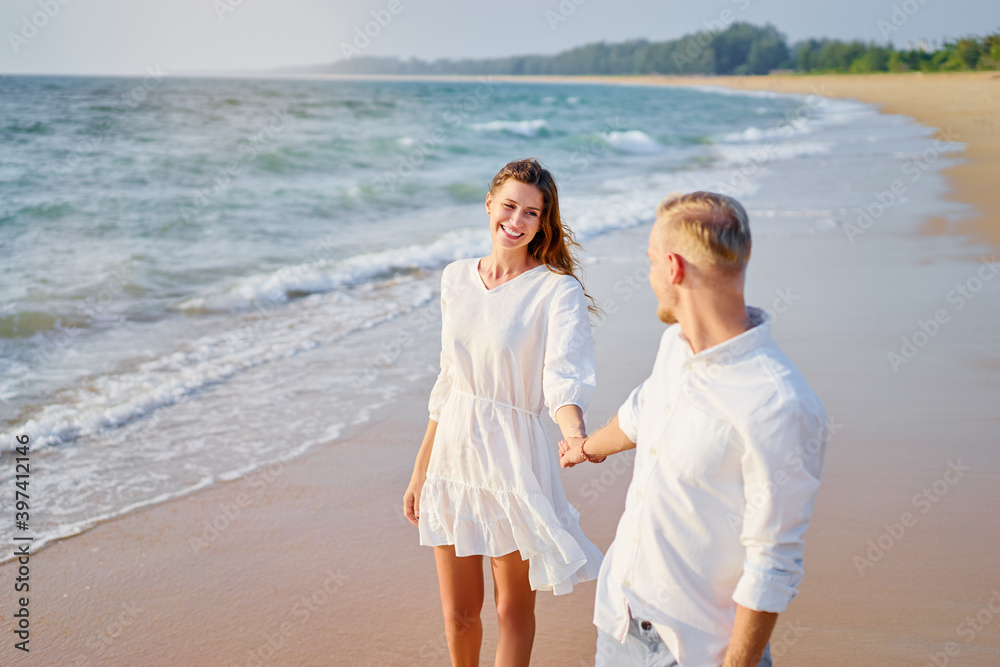 Romantic dating. Young loving couple walking together by the sand beach enjoying sea