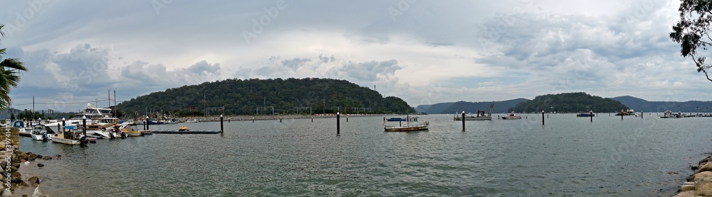 Beautiful panoramic view of a river on a cloudy day with tall mountains and trees in the background, Hawkesbury river, Brooklyn, New South Wales, Australia

