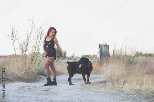 Modelo posando para una sesión en el campo con cadenas y un perro