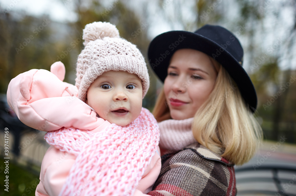 Beautiful baby girl with mother outdoors. Family outdoor. Adorable little girl in warm clothes in autumn park on sunny day. Pretty little girl with mom Beautiful baby girl with mother outdoors. Family outdoor. Adorable little girl in warm clothes in autumn park on sunny day. Pretty little girl with mom