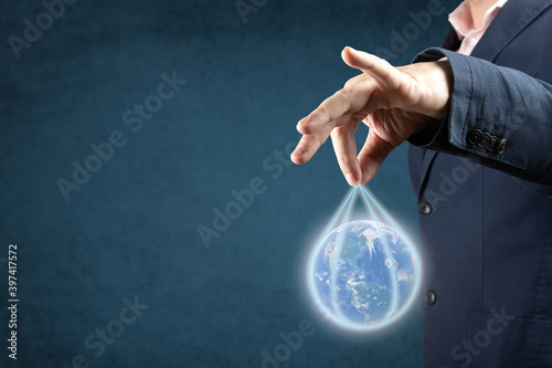 businessman holds planet earth. corporations run the world globalization concept. blue background. copyspace photo
