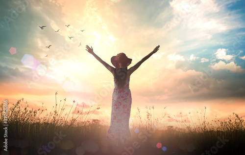 Worship concept: Silhouette of healthy woman raised hands for praise and worship God at autumn sunset meadow background photo