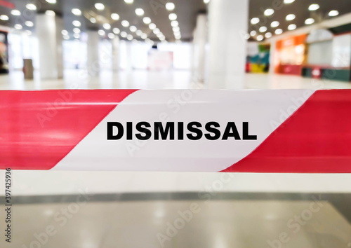 The word Dismissal on a red ribbon indoors. Unemployment due to crisis and virus pandemic.