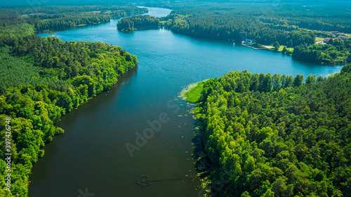 Big river between green forests at sunrise in summer
