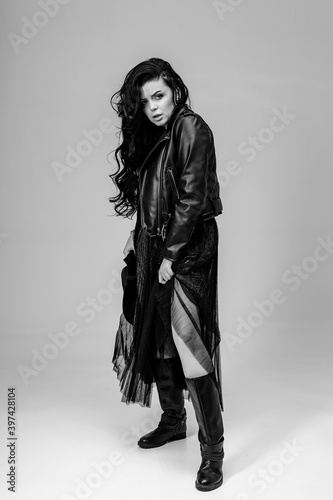 Full length portrait of a beautiful woman in dark gothic clothes and long dark hair. Black and white portrait.