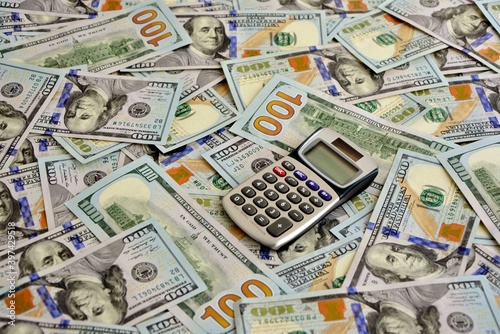 Calculator on the background of hundred-dollar bills. The concept of wealth and prosperity in business.