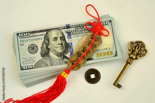 Valokuva A bundle of 100 dollar bills, a key, and сhinese feng shui coins  talismans to a