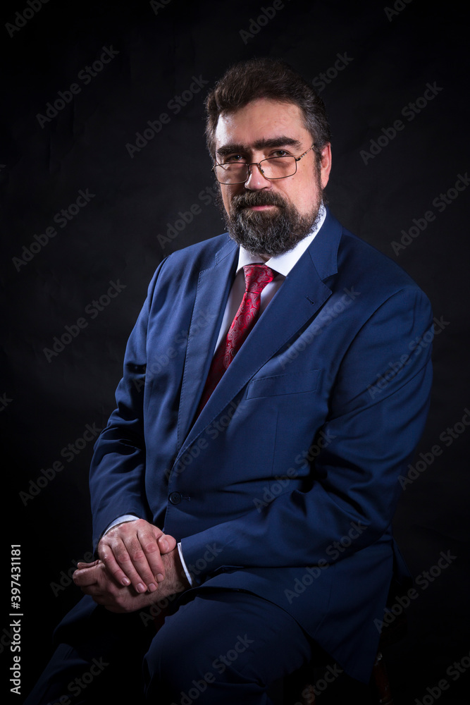 Fototapeta premium Mature businessman dressed in blue suit with red tie studio portrait.