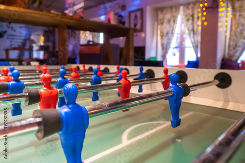 The game of table football. Table football field on the background of the recreation room. Games for children and adults. Enthusiasm. Battle. Desire to win. We help plastic players score goals.