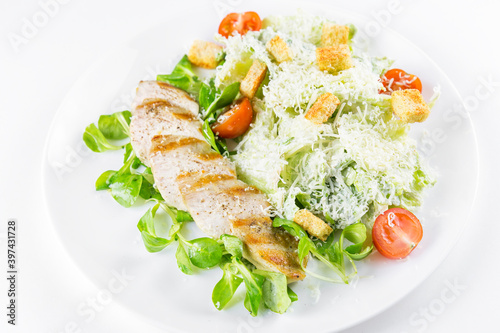 Croutons salad and grilled chicken fillet on a white dish