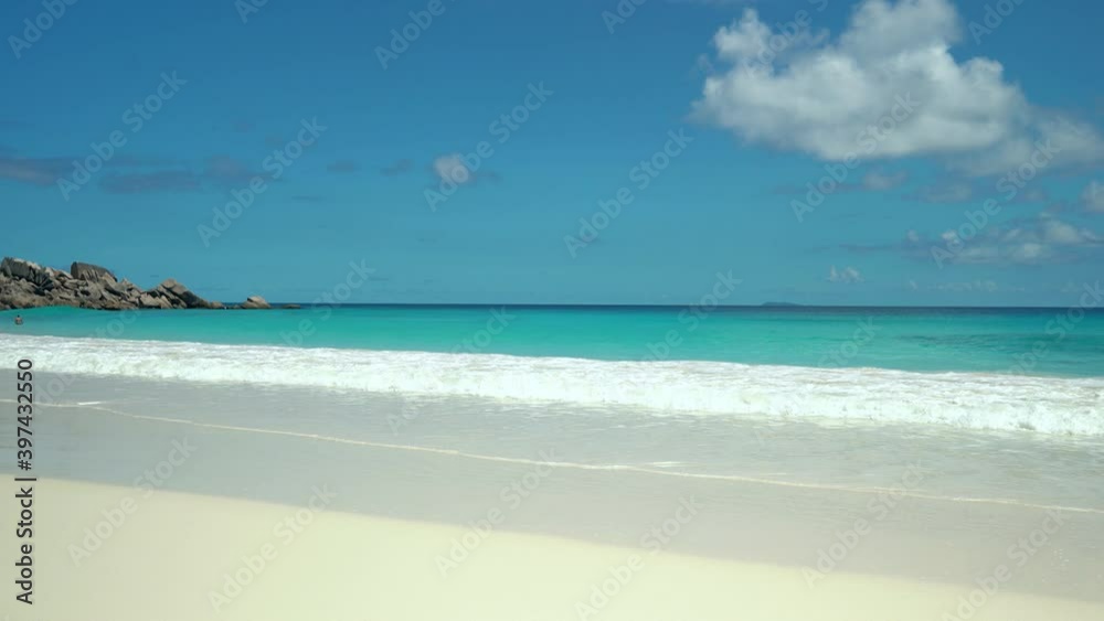 Exotic beach by the ocean with rolling waves on the sandy shore and blue sky Exotic beach by the ocean with rolling waves on the sandy shore and blue sky