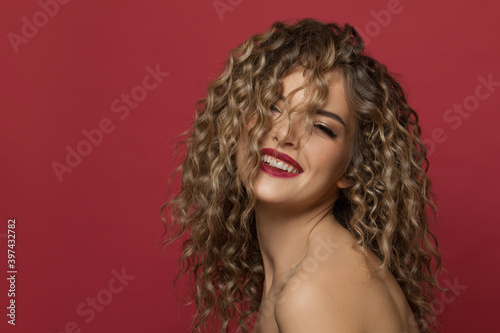 Fashion model woman with curly hair on red background